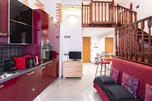 Une cuisine moderne avec des meubles de rangement rouges, un four à micro-ondes et une cuisinière. Un escalier en bois mène à un niveau supérieur.