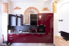 Une cuisine moderne avec des meubles rouges, un four à micro-ondes, une cuisinière et un téléviseur.
