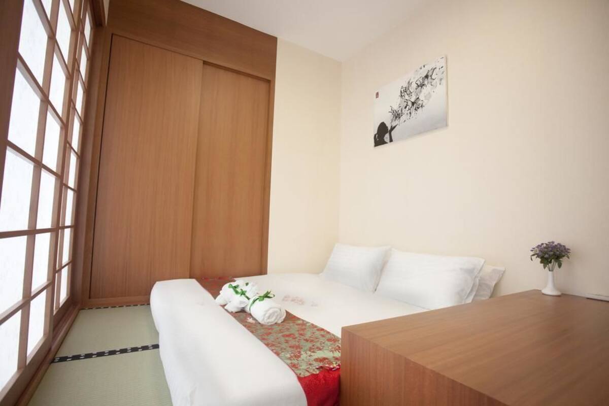 Une chambre d’hôtel avec un lit, un bureau en bois, une petite table et une fenêtre donnant sur un paysage agréable.