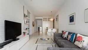 A modern living room with a flat-screen TV, a glass coffee table, and a grey sofa with colorful cushions. - Elysees Suite Marc Residence KLCC (Kuala Lumpur)