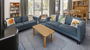 Un salon avec un canapé d’angle, une table basse en bois et une bibliothèque remplie de livres.