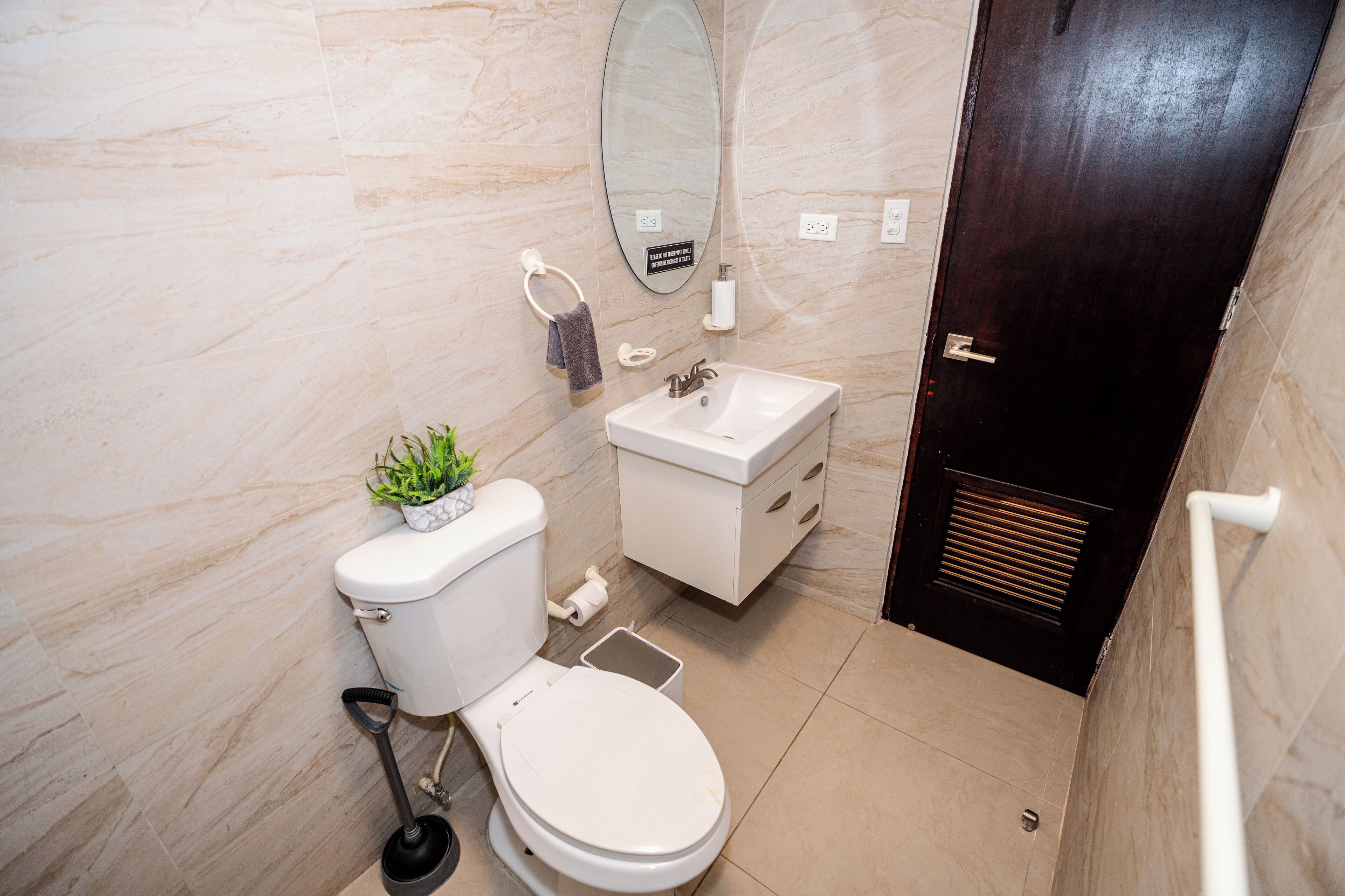 Une salle de bain moderne avec des toilettes, un lavabo, un miroir et une porte sombre.