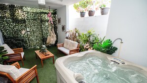 Un espacio de spa con jacuzzi, mobiliario de madera y plantas en macetas.