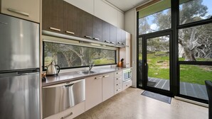 A modern kitchen with stainless steel appliances, a large window, and a view of the outdoors. - Ecocrackenback Luxe Chalet 19 (CRACKENBACK)