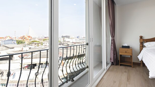 A bedroom with a large window, a wooden nightstand, a bed, and a view of the cityscape. - Royale 8 Ville (Bangkok)