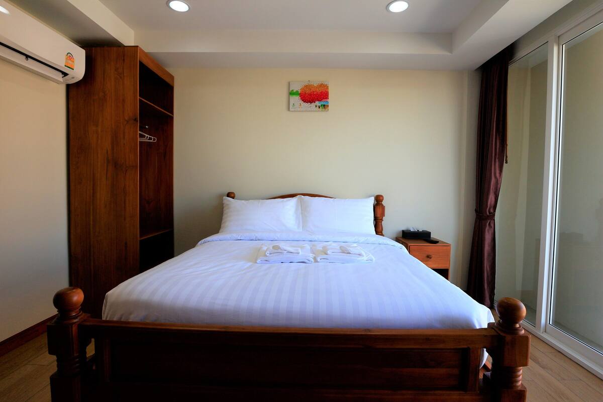 A neatly made bed with white linens, a wooden headboard, and a small bedside table with a lamp.