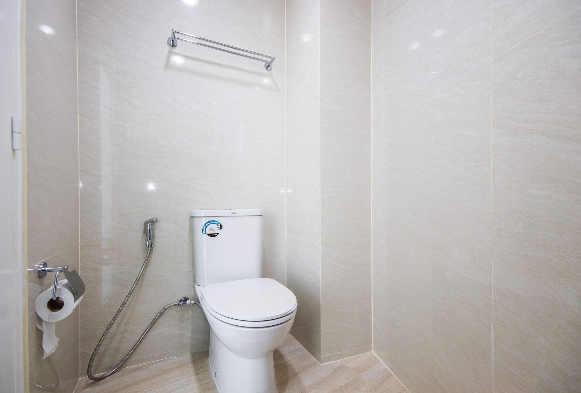 A modern bathroom with a toilet, a shower, and a towel rack.