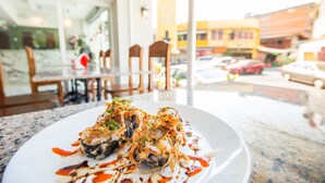 A sushi dish on a plate with a view of a restaurant interior and a street outside. - Royale 8 Ville (Bangkok)