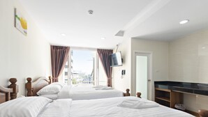 A hotel room with two beds, a TV, a desk, and a window with curtains. - Royale 8 Ville (Bangkok)