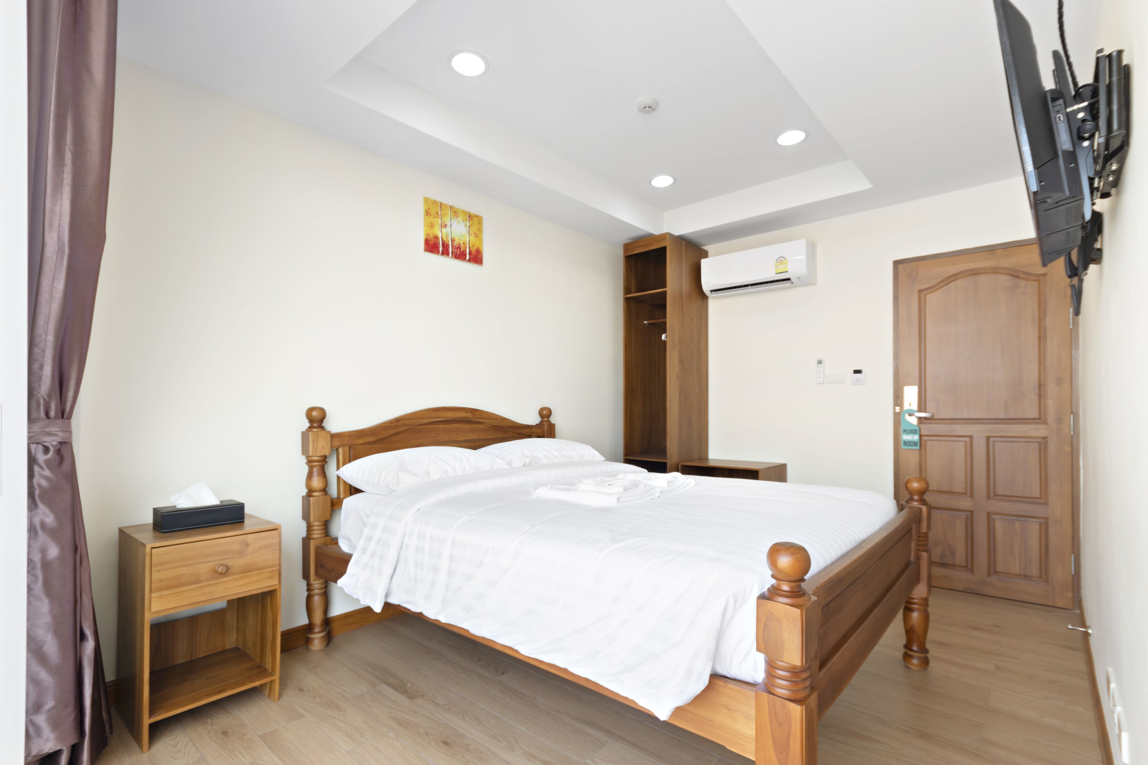 Quarto com cama de madeira, mesa de cabeceira, guarda-roupa e televisão na parede.
