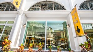 A hotel entrance with a sign reading "Regale & Ville" and two downward-pointing arrows on yellow banners. - Royale 8 Ville (Bangkok)
