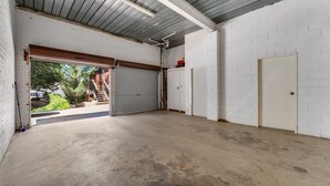 Un garage doté d’un sol en béton, de murs en briques blanches et d’un toit en métal.