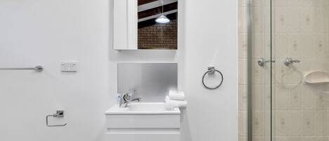 Une salle de bain moderne avec un lavabo blanc, un miroir et un porte-serviettes.