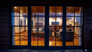 A wooden exterior with a glass door leading to a well-lit interior.