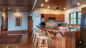 A spacious kitchen with wooden cabinets, a large island with bar stools, a built-in oven, and a refrigerator.