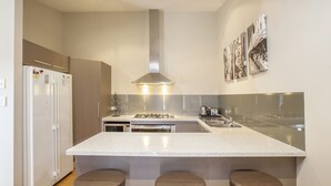 Una cocina moderna con una isla central, electrodomésticos de acero inoxidable y una galería de cuadros en la pared.