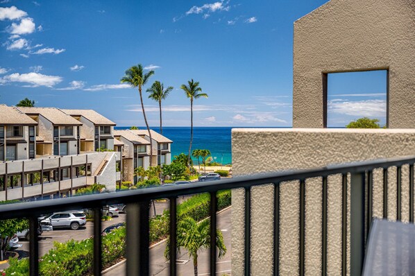 A beachfront hotel with multiple-story buildings, a parking area, and a view of the ocean.