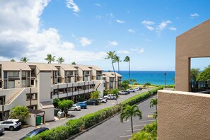 A multi-story hotel with a parking lot and a view of the ocean.