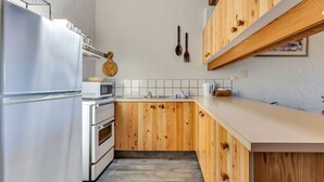 A compact kitchen with wooden cabinets, a white refrigerator, a microwave, and a stove.