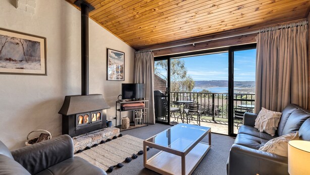 A cozy living room with a fireplace, a television, and a balcony with a scenic view.