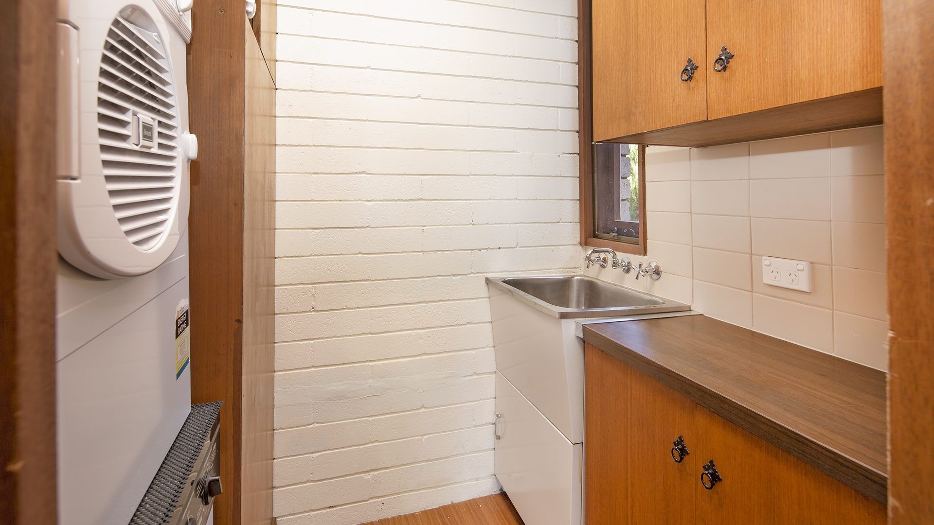 A compact kitchen with a built-in sink, wooden cabinets, and a white wall.