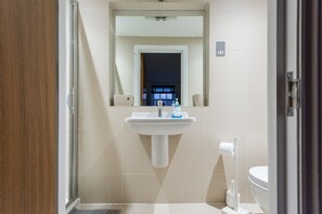 Une salle de bain avec un lavabo, un miroir et des toilettes.