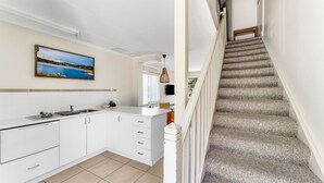 A modern kitchen with white cabinetry, a large island, and a painting of a landscape.
