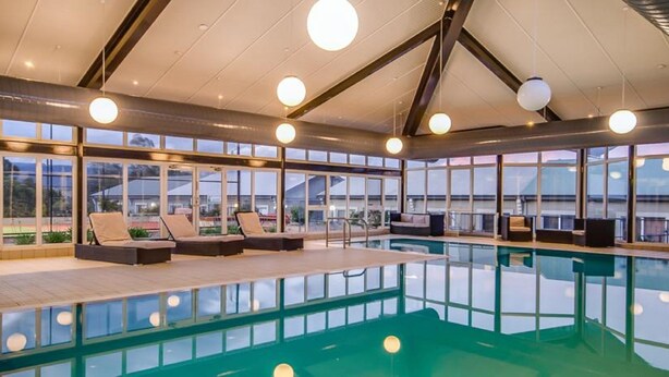 Une piscine intérieure moderne, dotée de chaises longues et offrant une vue sur les environs.