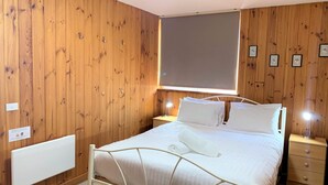 A wooden-paneled room with a bed, bedside tables, and a window. - Seeblick 3 - 1BR Lakefront Apartment l Central Location l Off Street Parking (JINDABYNE)
