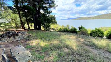 Une propriété au bord du lac, avec des murs en pierre, un banc en bois et de nombreux arbres.