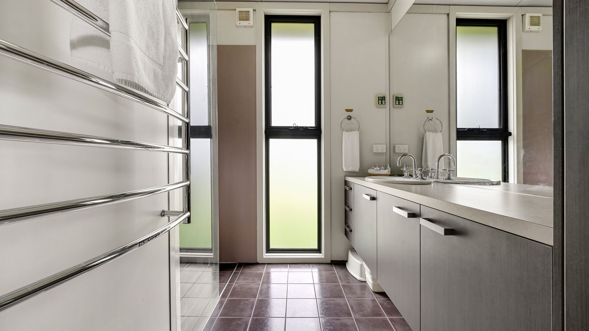 Ein modernes Badezimmer mit großem Spiegel, Waschbecken und Toilette.