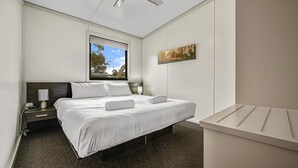 A hotel room with a bed, bedside lamps, a window with a view of trees, and a painting on the wall. - Ecocrackenback 7 'Sustainable chalet close to the slopes.' (Crackenback)