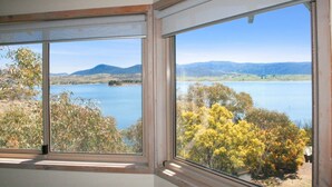 Ein Zimmer mit zwei großen Fenstern, das Blick auf einen See und die umliegende Landschaft bietet.