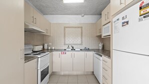 A compact kitchen with a stove, microwave, and sink. - Central Park 4 - 3BR Ground Floor Apartment l Central Location (Jindabyne)