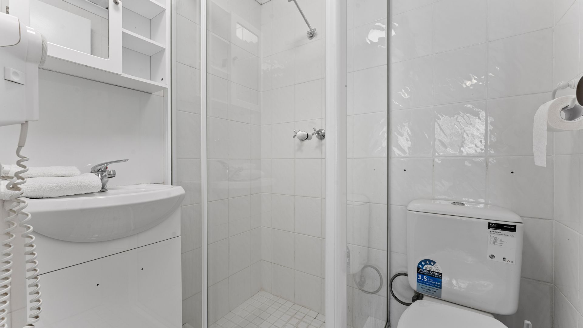 Uma casa de banho moderna com uma sanita branca, lavatório e área de duche.