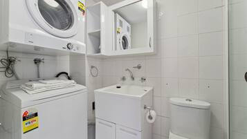 A modern bathroom with a front-loading washer, a sink, and a toilet.
