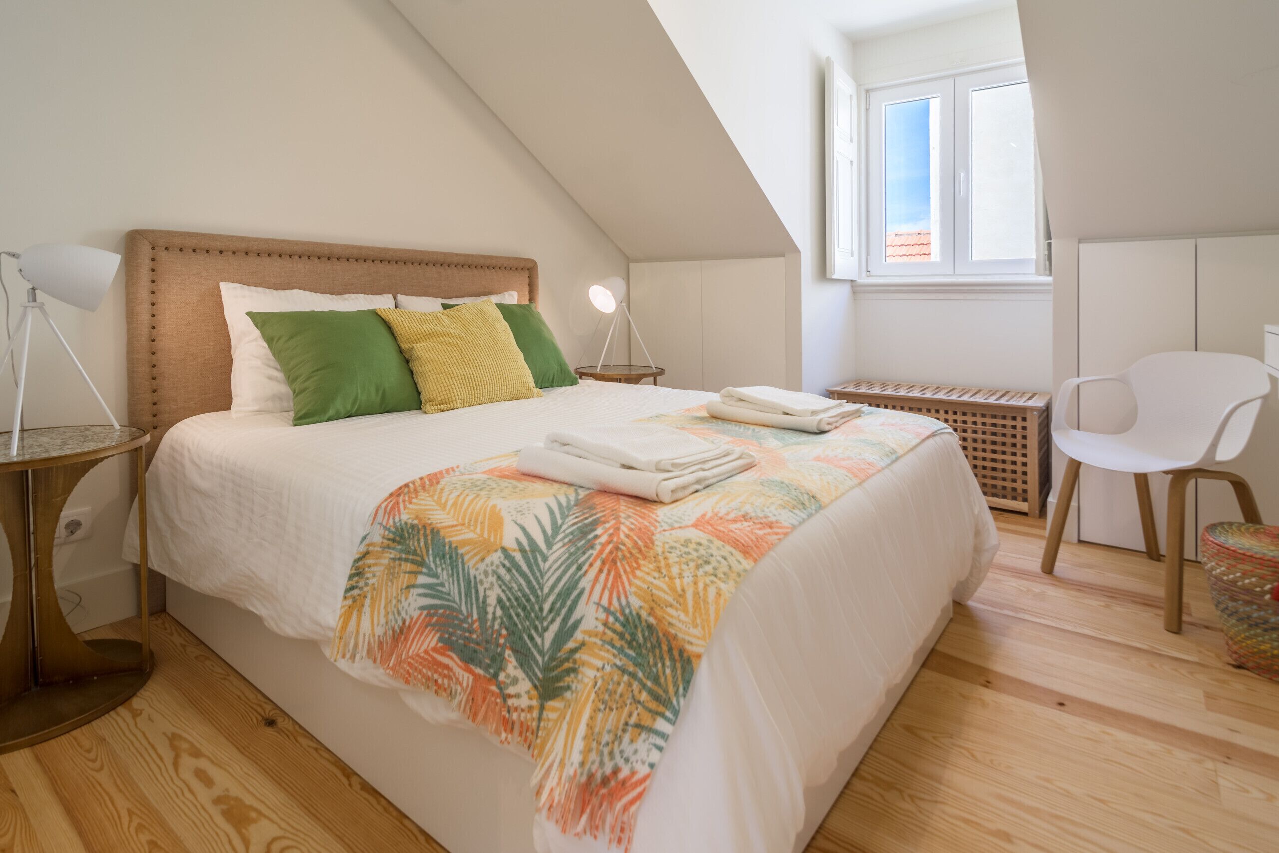 Un dormitorio con cama, escritorio, silla, lámpara y ventana.
