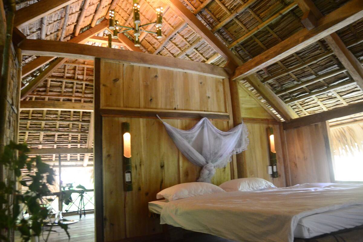 Een houten kamer met een bed, een hangwieg en een houten plafond.