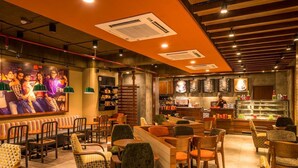 A restaurant interior with booths, tables, and a bar area. - Hotel Inclover (Dharamshala)