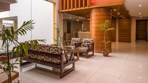 A modern lobby with a reception desk, seating area, and a staircase. - Hotel Inclover (Dharamshala)