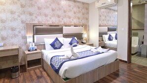 A hotel room with a large bed, a wooden nightstand, a desk, and a trash bin. - Hotel Inclover (Dharamshala)