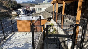 Un espace clos, avec un bâtiment en briques et une structure en bois, peut-être un hôtel ou une maison d’hôtes, offrant une vue sur les montagnes en arrière-plan.
