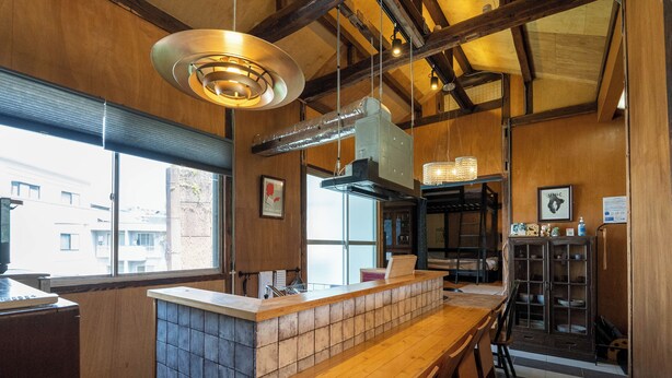 Une cuisine avec un comptoir en bois, des luminaires suspendus et une vue sur la rue.