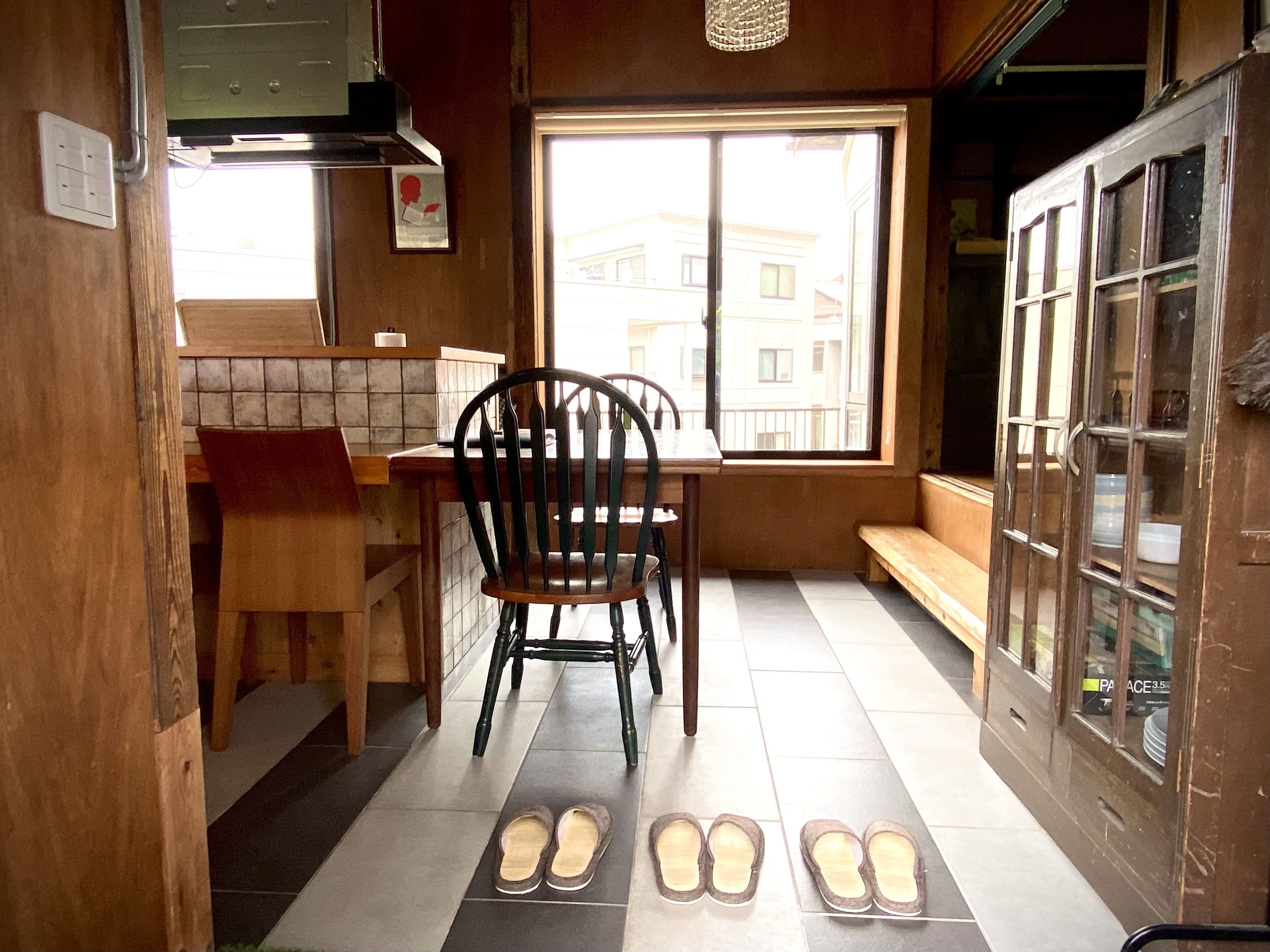A kitchen with a wooden table, a chair, and a window with a view of buildings.