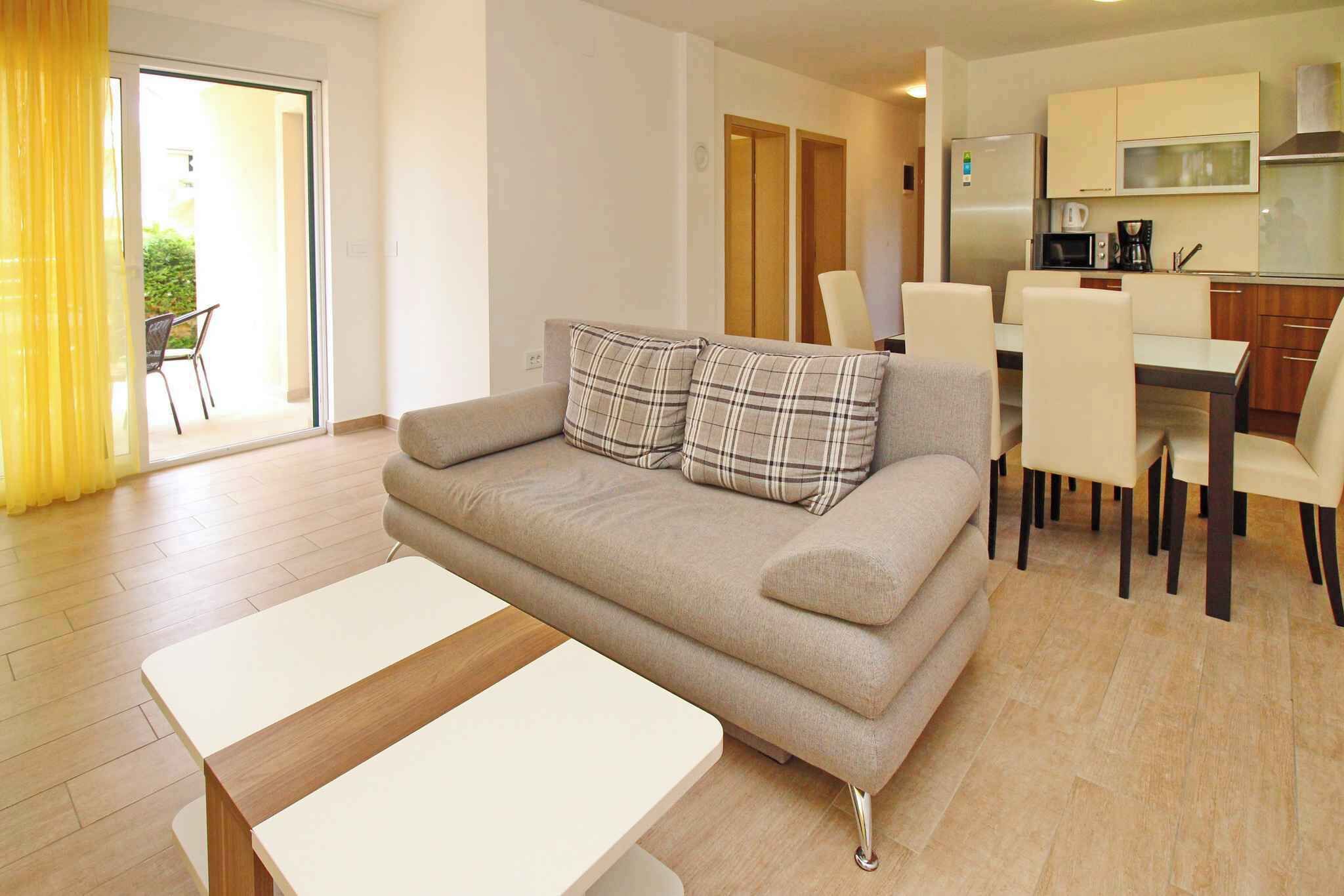 A modern living room with a sofa, a dining table, and a kitchen area.