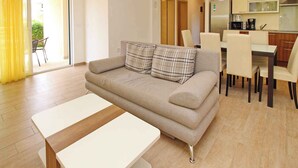 Ein modernes Wohnzimmer mit einer Couch, einem Esstisch und einer Küchenzeile.