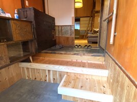A wooden interior with a built-in bench, a small step leading to a higher level, and a pair of shoes on the step.