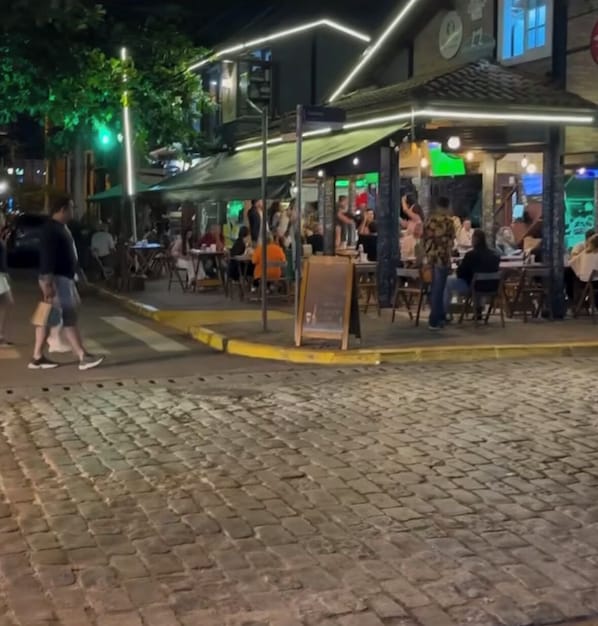 A cobblestone street with outdoor seating at a restaurant.