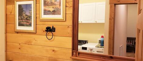 A bathroom with wooden paneling, a white toilet, a black sink, and two framed pictures on the wall.