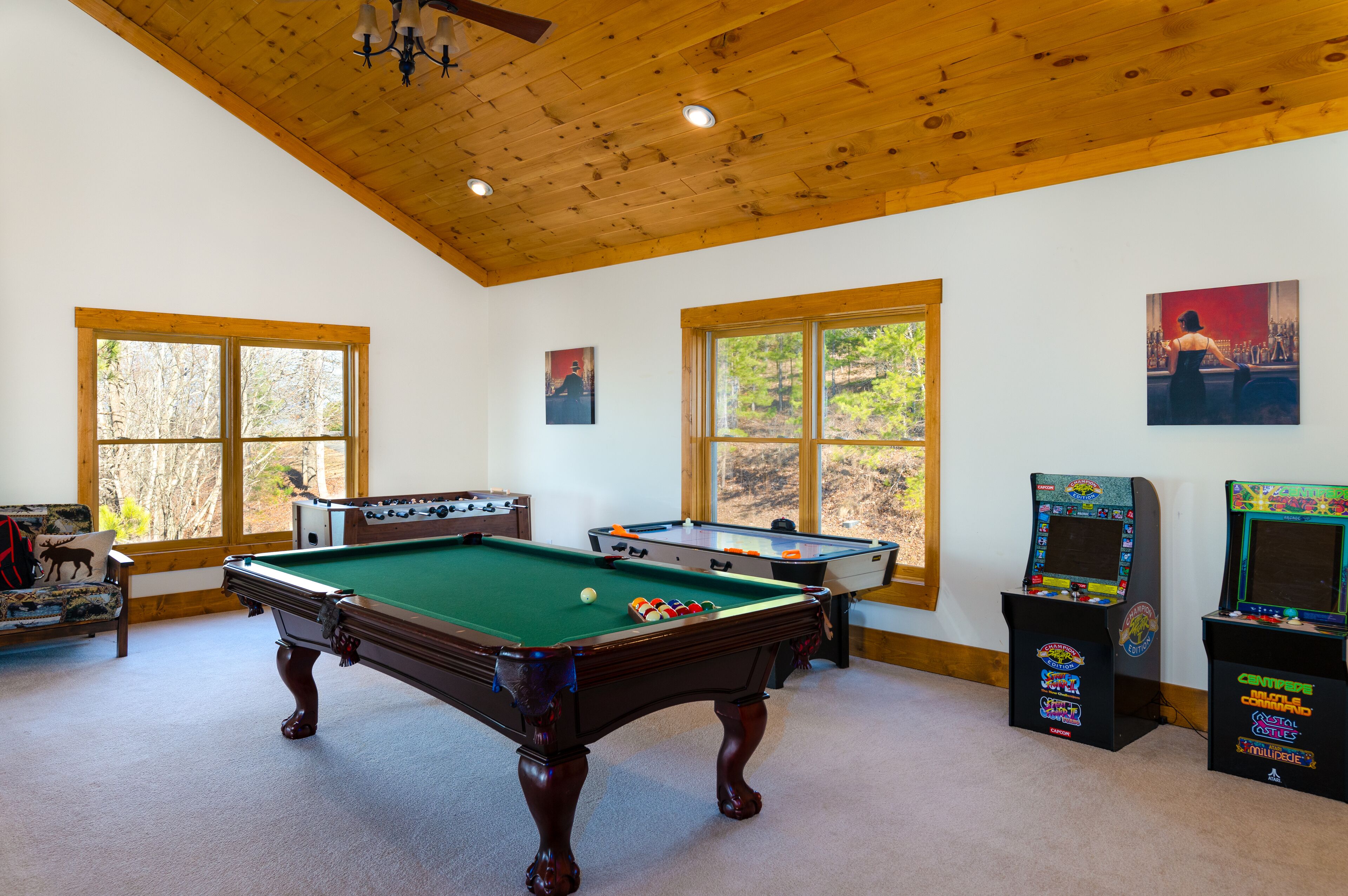 Une table de billard dans une pièce dotée de plafonds en bois et de grandes fenêtres.